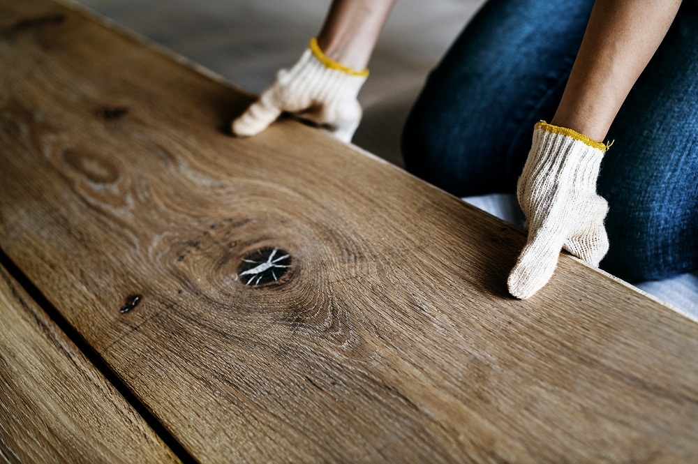 Man holding piece of wood while wearing gloves