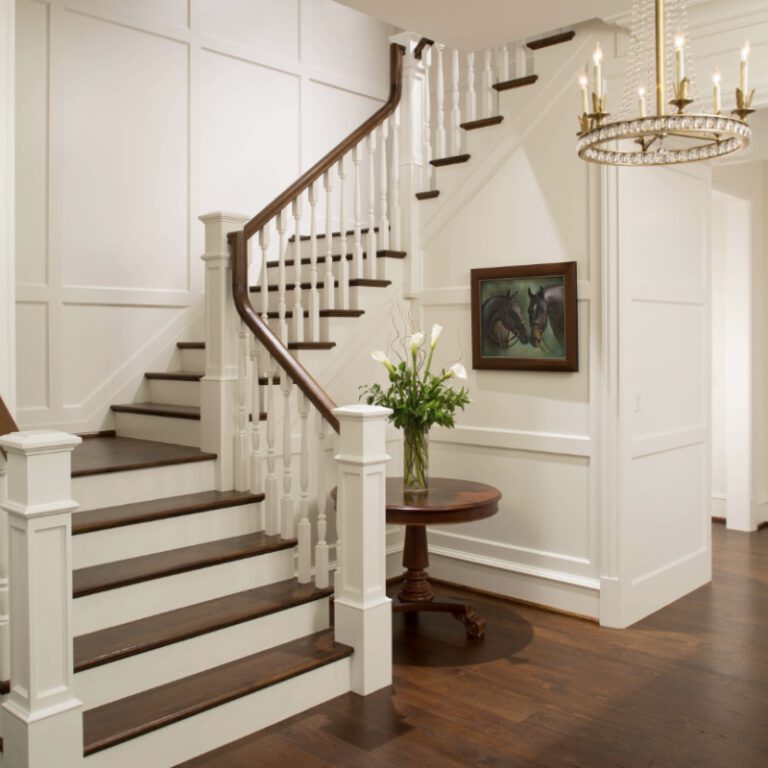 Curved staircase remodel detail with dark treads and white wainscoting