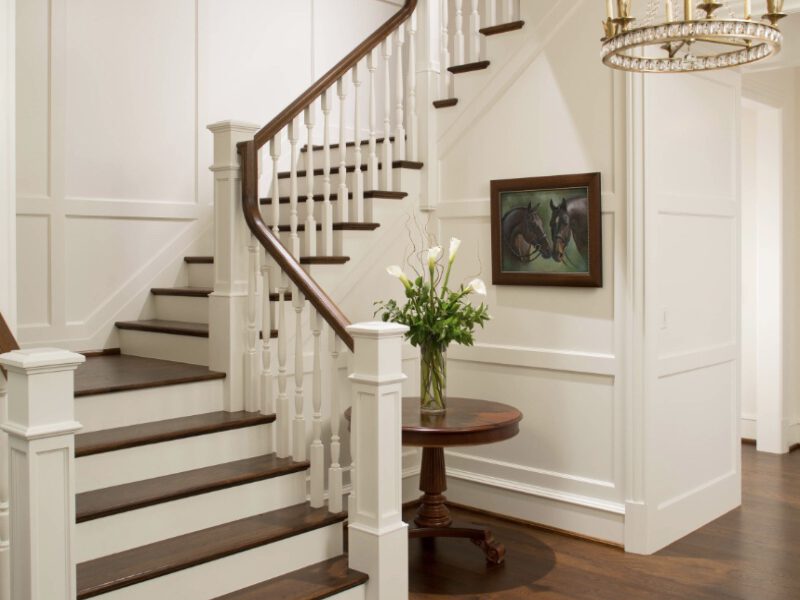 Finished curved staircase remodel with dark stained treads, white spindles and wainscoting