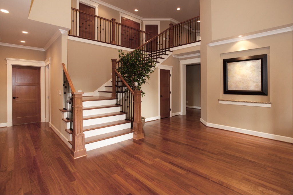 Finished staircase with iron balusters and hardwood flooring in a two-story foyer