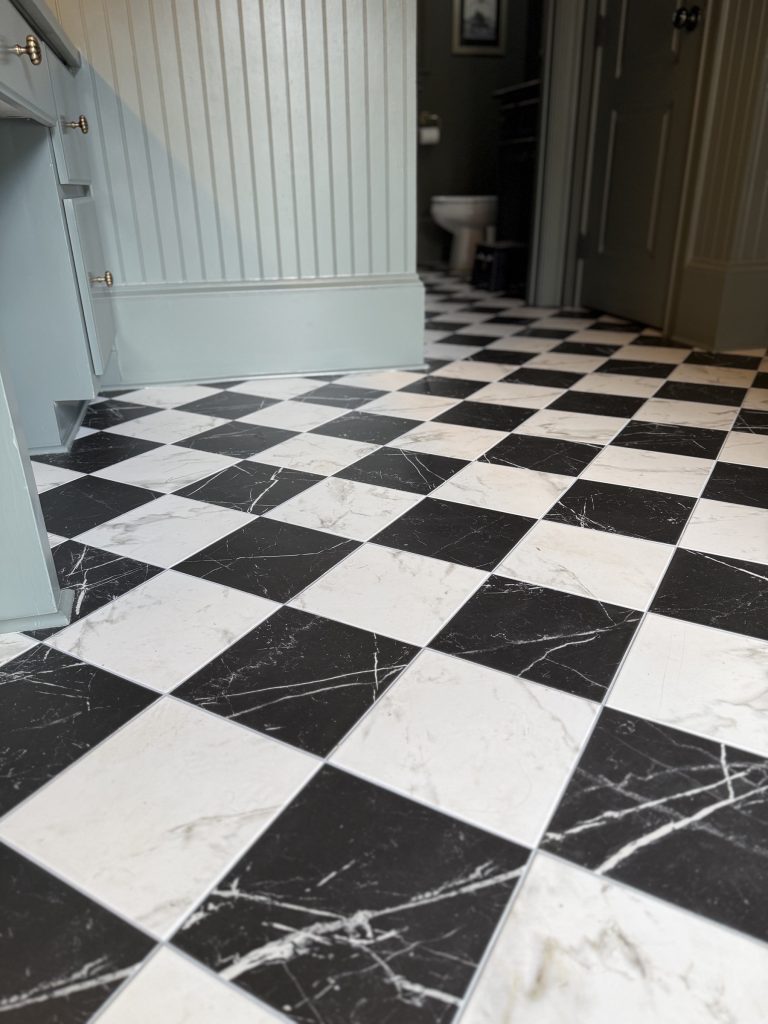Black and white marble-look checkerboard tile floor running into the bath in a Milton, GA home, installed by Atlanta Floor One