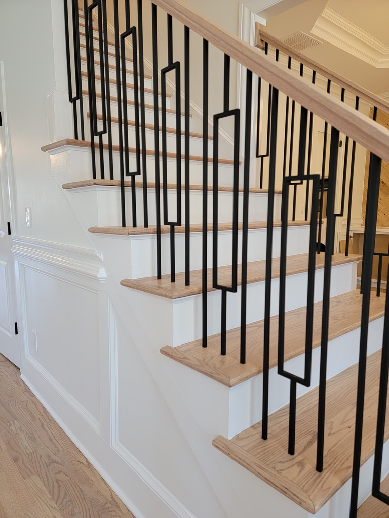 Remodeled staircase with natural oak treads, white risers and black metal balusters by Atlanta Floor One