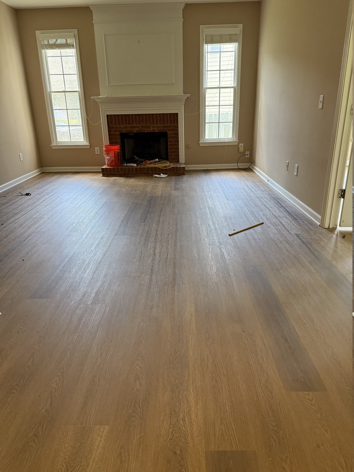 Luxury vinyl plank flooring newly installed in an Alpharetta, GA living room, planks running toward a brick fireplace