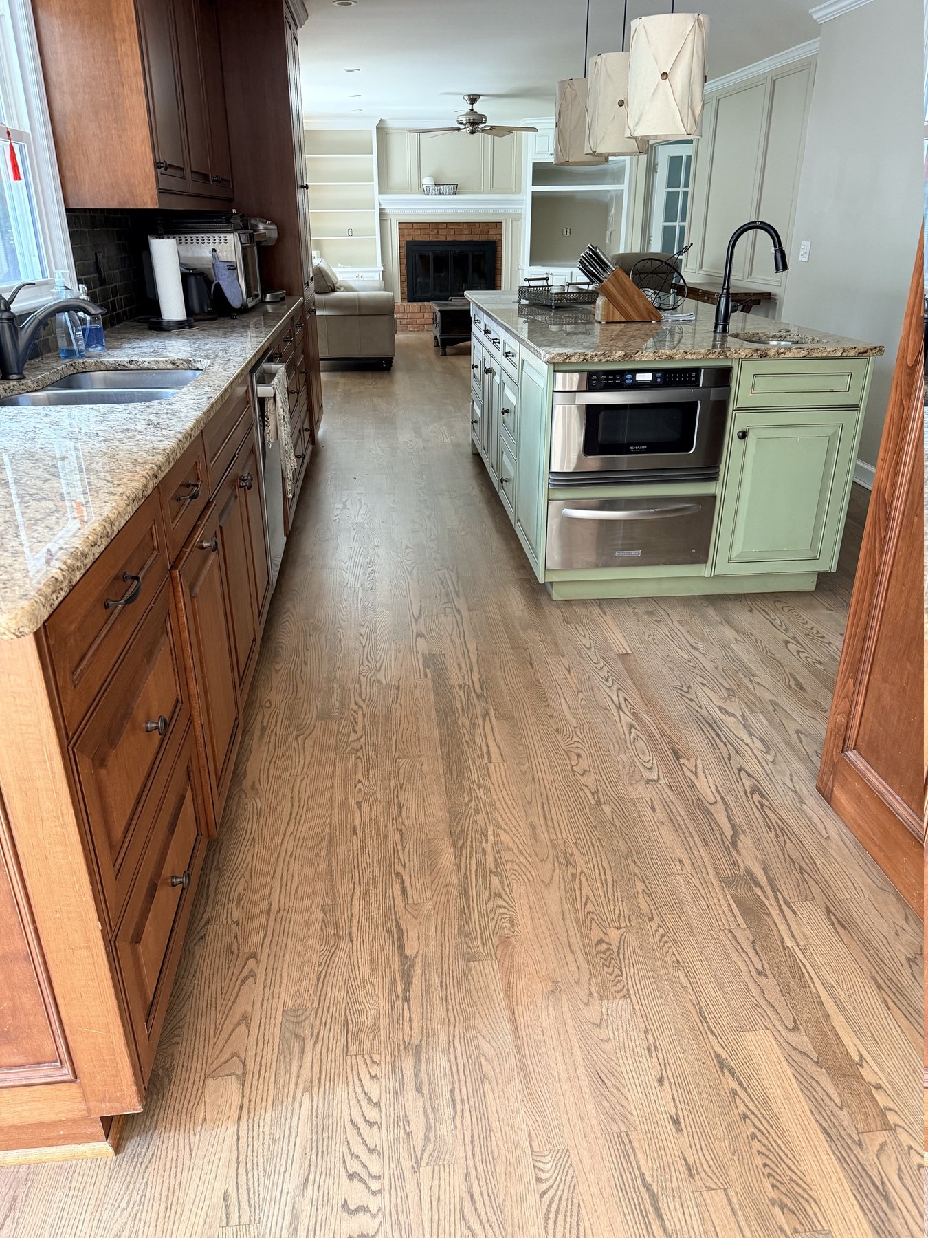 Refinished red oak hardwood floor running from the kitchen into the open living area of a Peachtree Corners, GA home