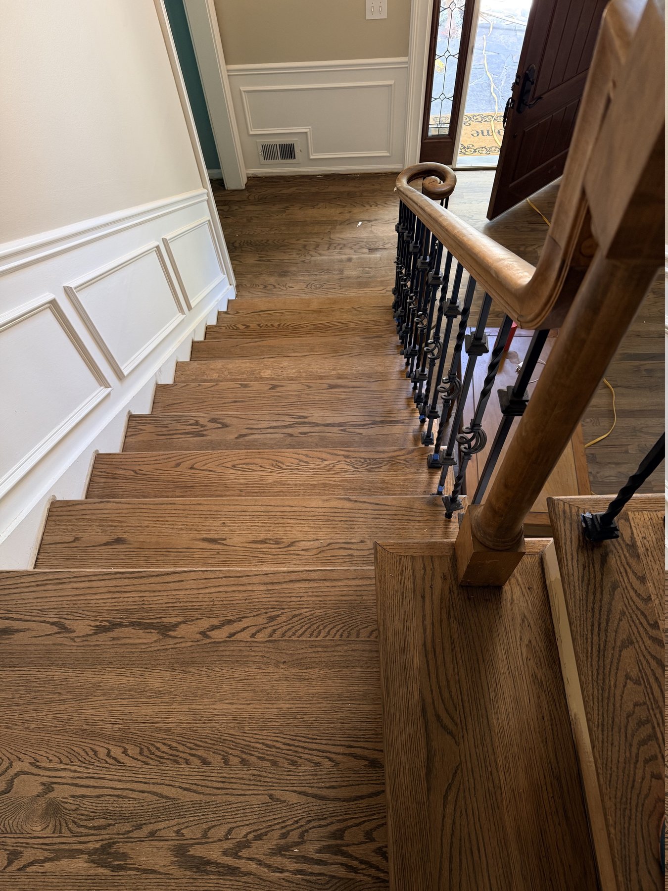 Refinished red oak stair treads and foyer floor with iron balusters and an oak handrail in a Peachtree Corners, GA home